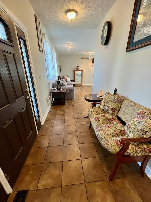 interior space featuring dark tile patterned flooring, visible vents, a textured ceiling, and baseboards