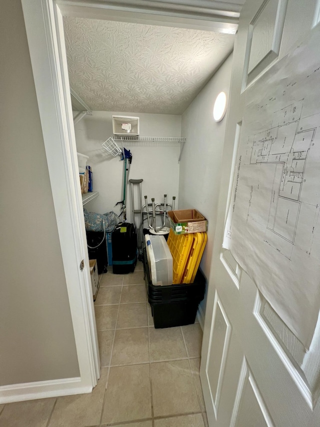 interior space with a textured ceiling, baseboards, and light tile patterned floors