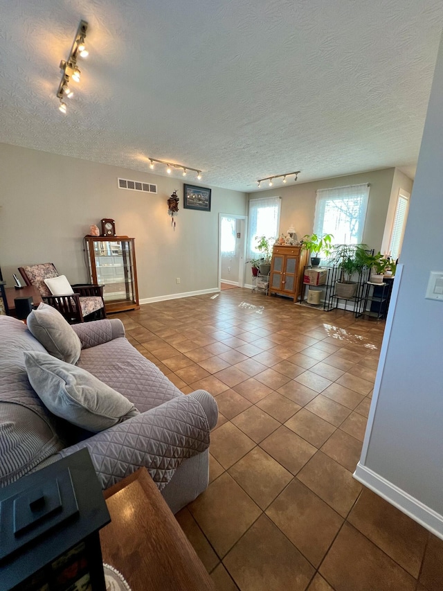 tiled living area with visible vents, a textured ceiling, and baseboards