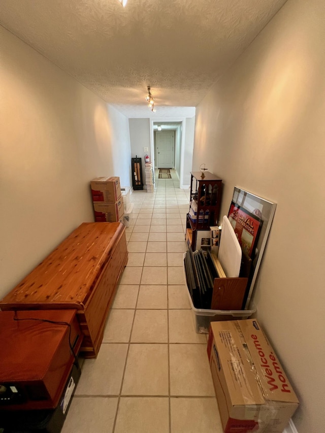 corridor featuring light tile patterned floors and a textured ceiling