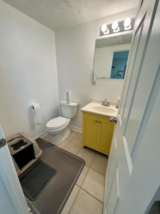 bathroom with toilet, a textured ceiling, vanity, tile patterned flooring, and baseboards