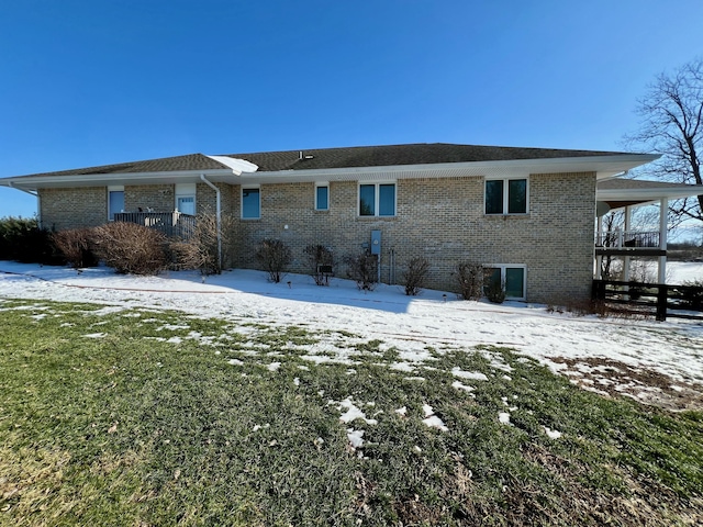 snow covered back of property with brick siding