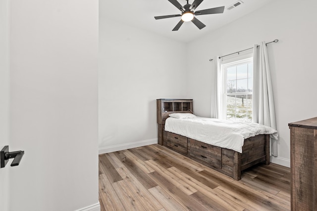 bedroom featuring ceiling fan, light wood-type flooring, visible vents, and baseboards