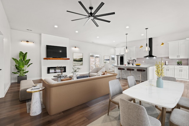 living area with a glass covered fireplace, dark wood finished floors, and recessed lighting