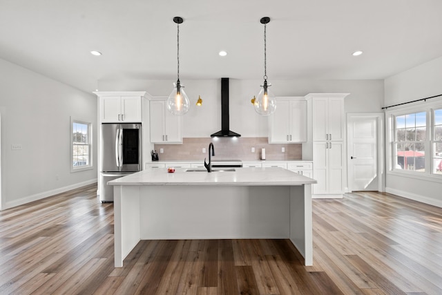 kitchen featuring light countertops, wall chimney range hood, smart refrigerator, and white cabinets