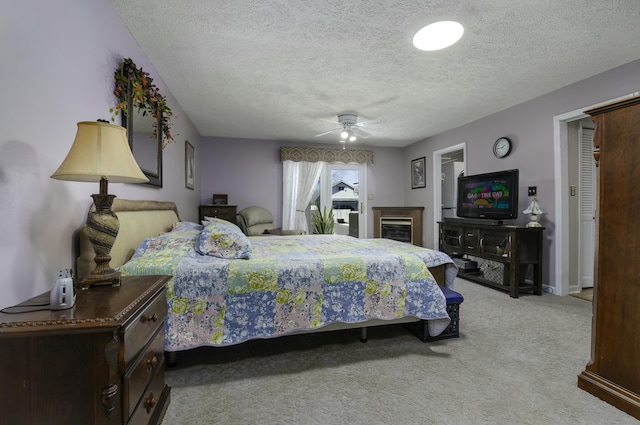 bedroom with ceiling fan, baseboards, a textured ceiling, and light colored carpet