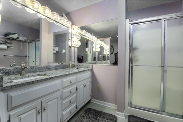 full bath with double vanity, a stall shower, and a sink