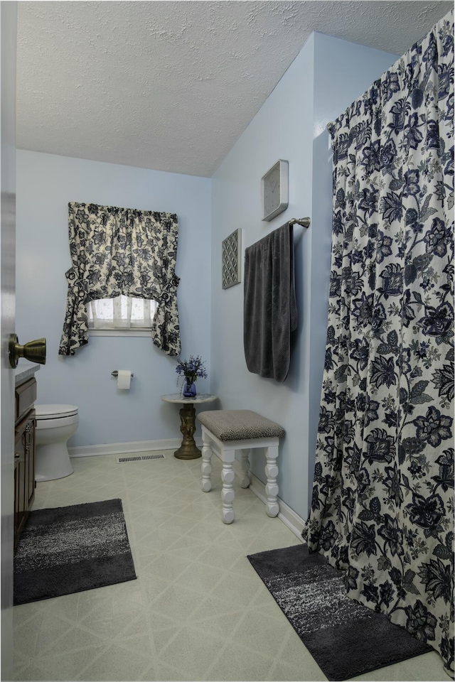 bathroom with baseboards, visible vents, a textured ceiling, and toilet