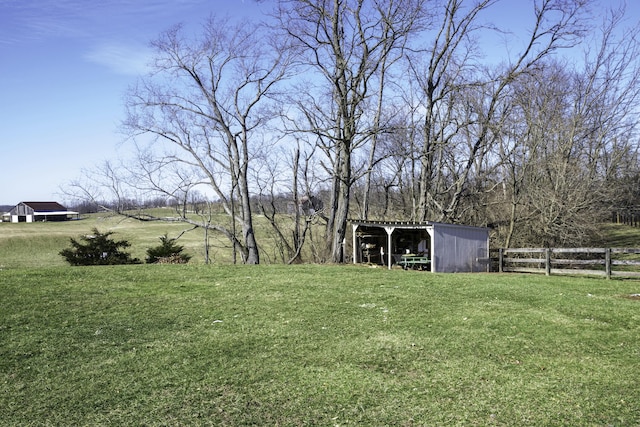 view of yard featuring an outbuilding, a pole building, a rural view, and fence