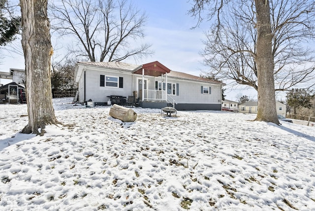 snow covered rear of property with metal roof