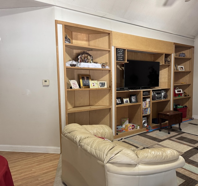 living area with light wood-type flooring, baseboards, and built in shelves
