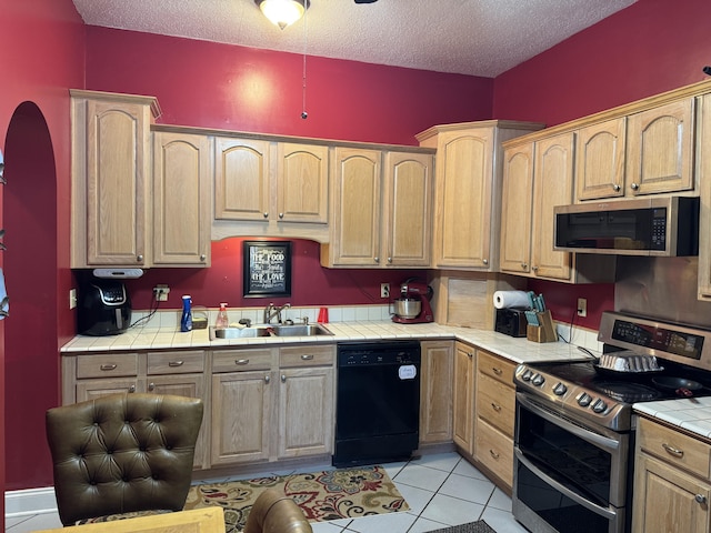 kitchen featuring a sink, tile counters, a textured ceiling, and stainless steel appliances
