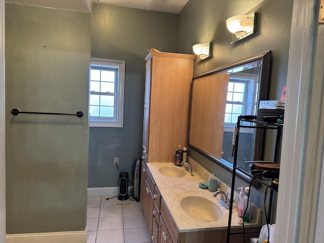 bathroom with double vanity, a sink, tile patterned flooring, and baseboards