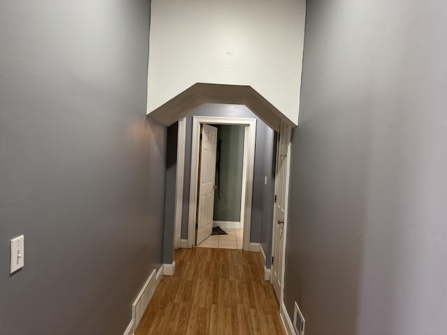 corridor featuring visible vents, baseboards, and light wood-type flooring