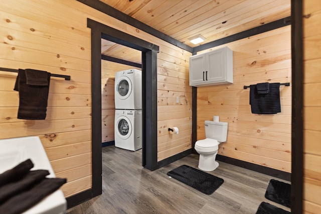 bathroom featuring stacked washer and dryer, wood ceiling, wooden walls, and wood finished floors