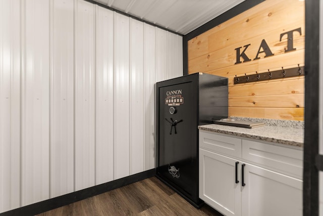 details with wooden walls, light stone counters, white cabinets, and dark wood-style flooring