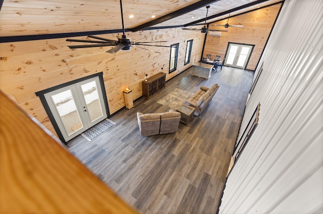 living room with french doors, wooden walls, wood finished floors, high vaulted ceiling, and beamed ceiling