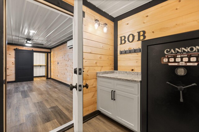 unfurnished bedroom featuring wood ceiling, freestanding refrigerator, an AC wall unit, and wood finished floors