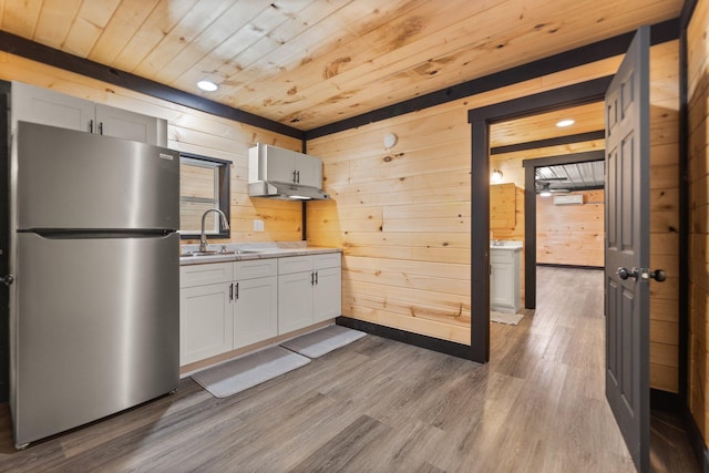 kitchen featuring light countertops, freestanding refrigerator, a sink, wood finished floors, and wooden ceiling