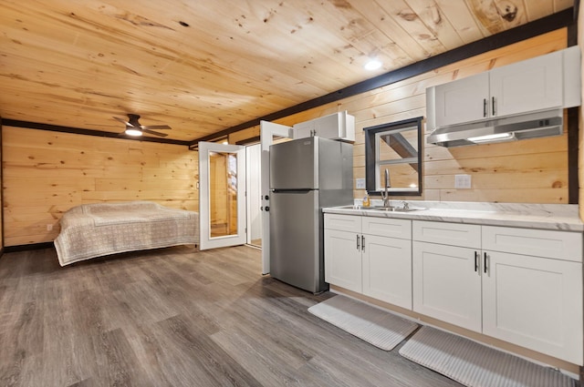 kitchen featuring freestanding refrigerator, a sink, white cabinetry, and under cabinet range hood