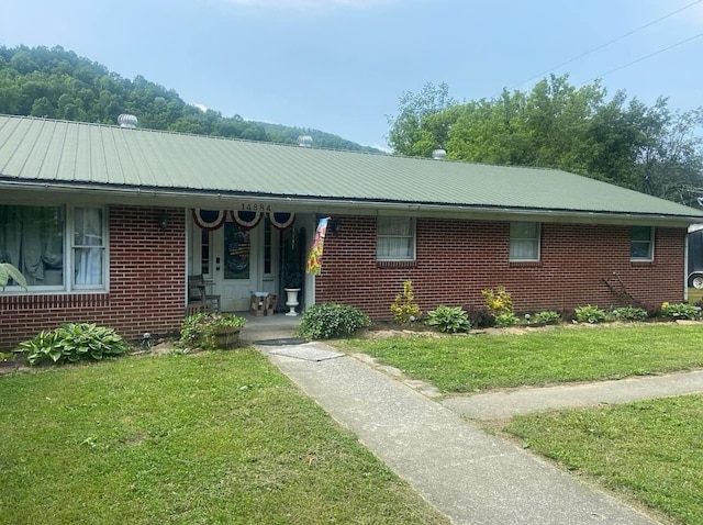 ranch-style home featuring metal roof, brick siding, and a front yard