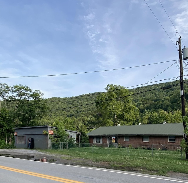 view of front of property featuring a forest view, a fenced front yard, and a front yard