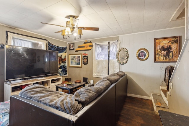 living area with a ceiling fan, dark wood-type flooring, and ornamental molding