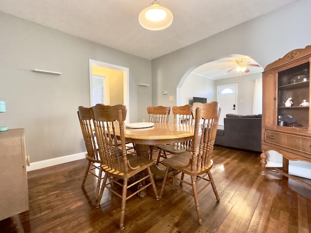 dining room with baseboards, arched walkways, and dark wood-type flooring