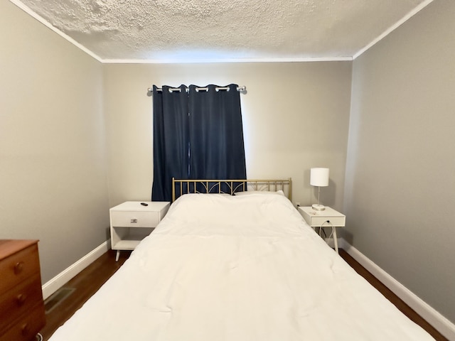 bedroom with dark wood-type flooring, ornamental molding, a textured ceiling, and baseboards