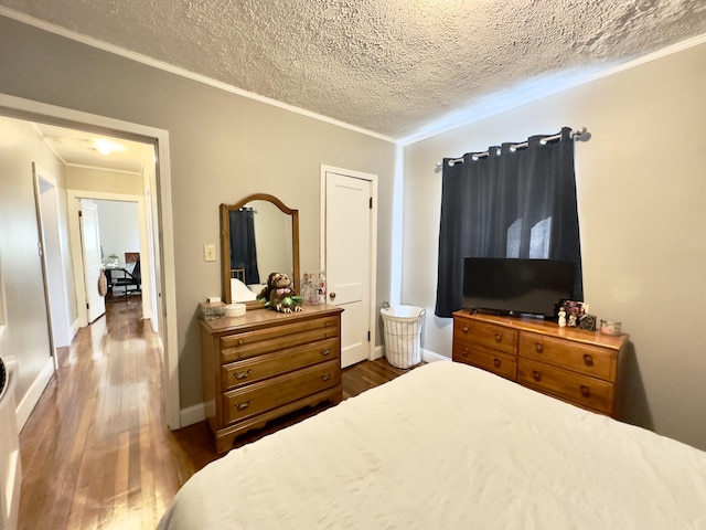 bedroom with crown molding, dark wood finished floors, a textured ceiling, and baseboards