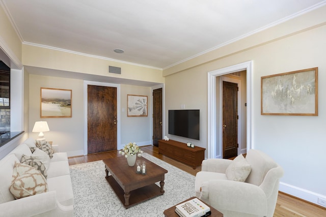 living room with light wood-style floors, baseboards, visible vents, and crown molding