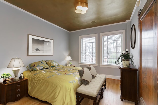 bedroom with light wood-type flooring, a barn door, baseboards, and crown molding