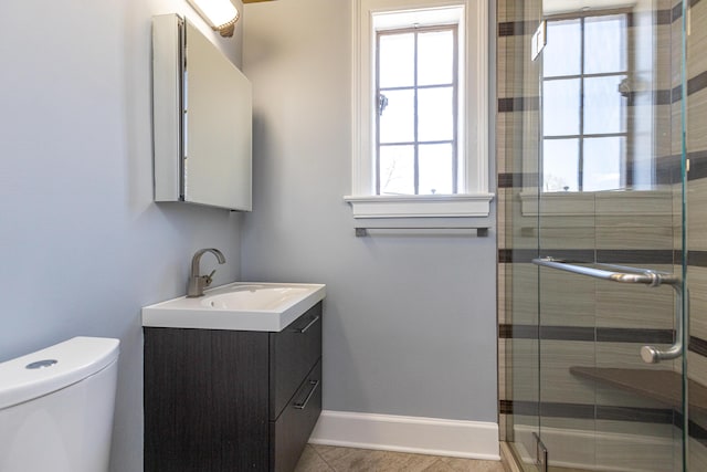 full bath with a stall shower, baseboards, vanity, and toilet