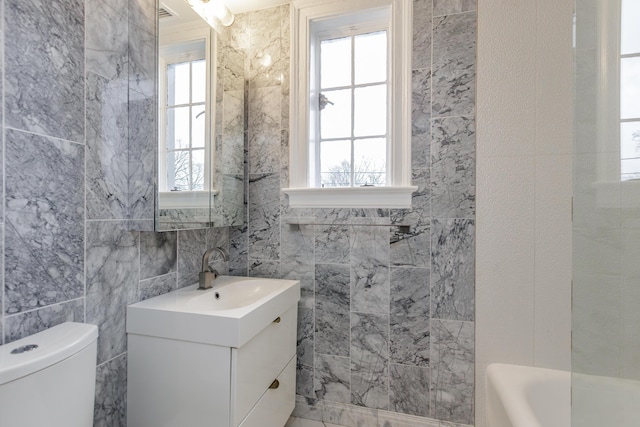 full bathroom featuring a bathing tub, vanity, toilet, and tile walls