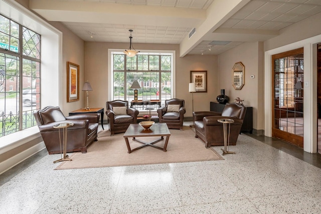 living room with baseboards, visible vents, a drop ceiling, and speckled floor