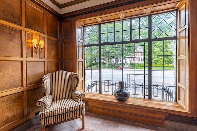 sitting room with wood walls, plenty of natural light, and crown molding