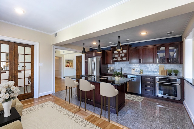 kitchen with stainless steel appliances, baseboards, glass insert cabinets, and a breakfast bar area