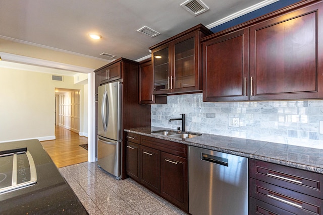 kitchen featuring granite finish floor, a sink, baseboards, appliances with stainless steel finishes, and glass insert cabinets