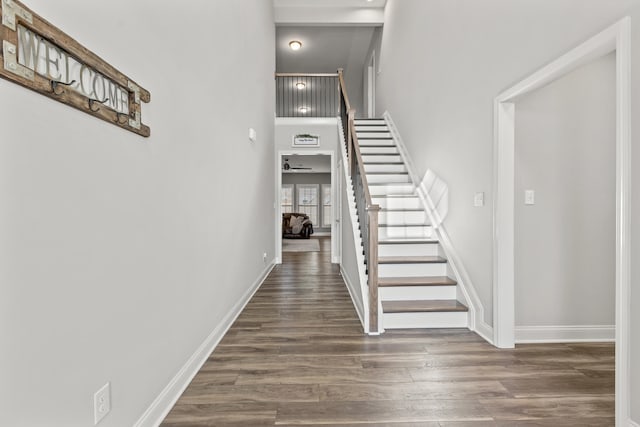 interior space featuring a high ceiling, stairway, dark wood finished floors, and baseboards