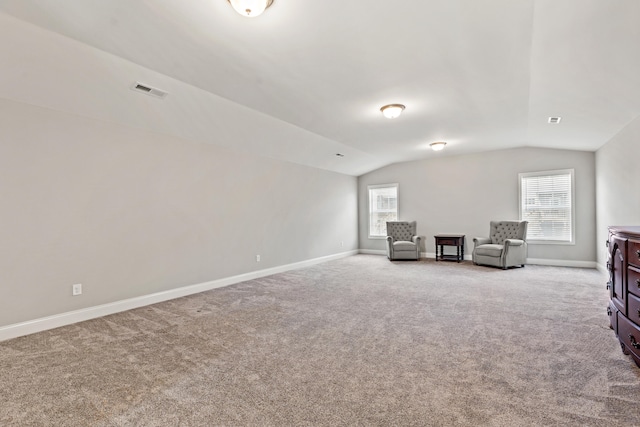 unfurnished room with lofted ceiling, visible vents, light colored carpet, and baseboards