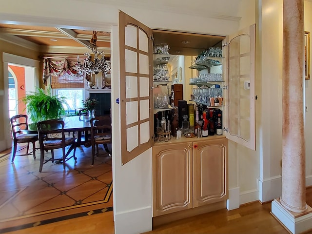 bar featuring wood finished floors, coffered ceiling, decorative columns, and an inviting chandelier