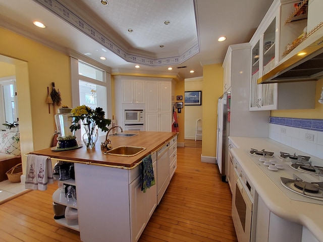 kitchen featuring white appliances, white cabinetry, open shelves, a raised ceiling, and glass insert cabinets