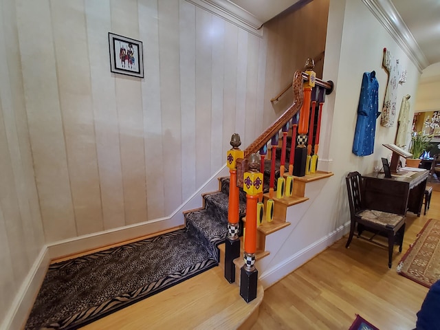 staircase with crown molding, baseboards, and wood finished floors