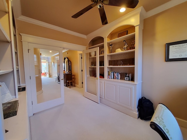 interior space featuring ceiling fan, built in shelves, light colored carpet, french doors, and crown molding