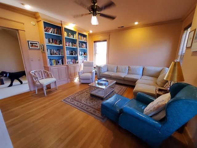 living room featuring ceiling fan, wood finished floors, visible vents, and crown molding