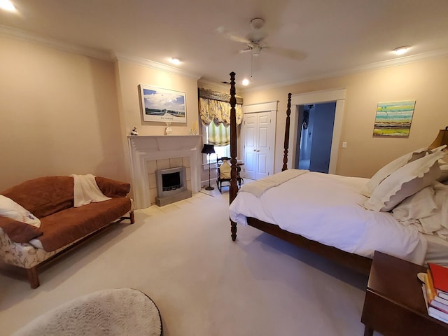 carpeted bedroom with a tile fireplace, crown molding, and ceiling fan