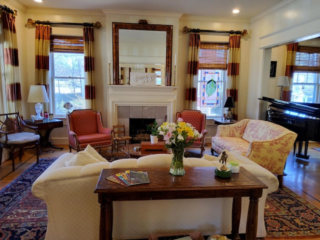 living area with a tiled fireplace, ornamental molding, and a wealth of natural light