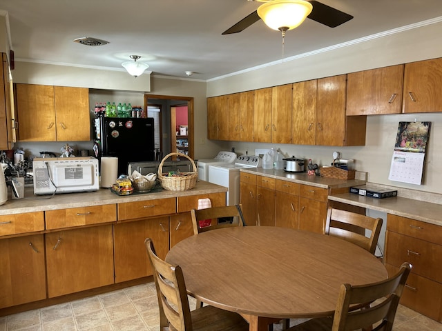 kitchen featuring light countertops, freestanding refrigerator, brown cabinets, and washer and clothes dryer