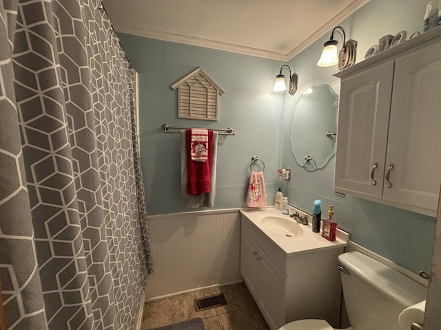 full bath featuring toilet, a wainscoted wall, vanity, visible vents, and crown molding