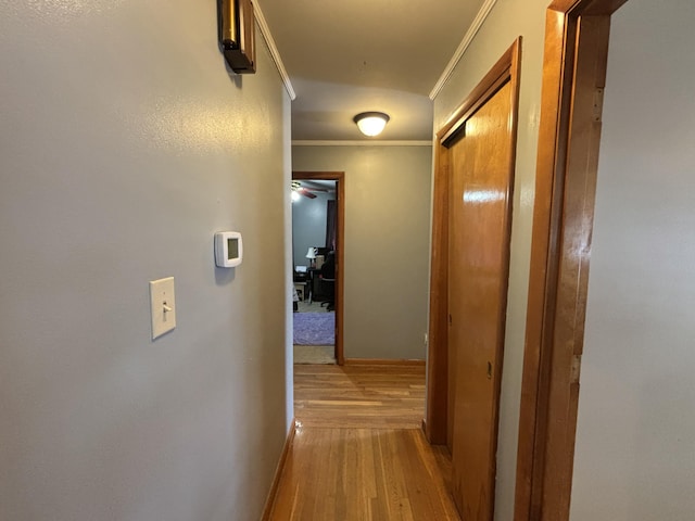 hallway with ornamental molding, light wood-style floors, and baseboards